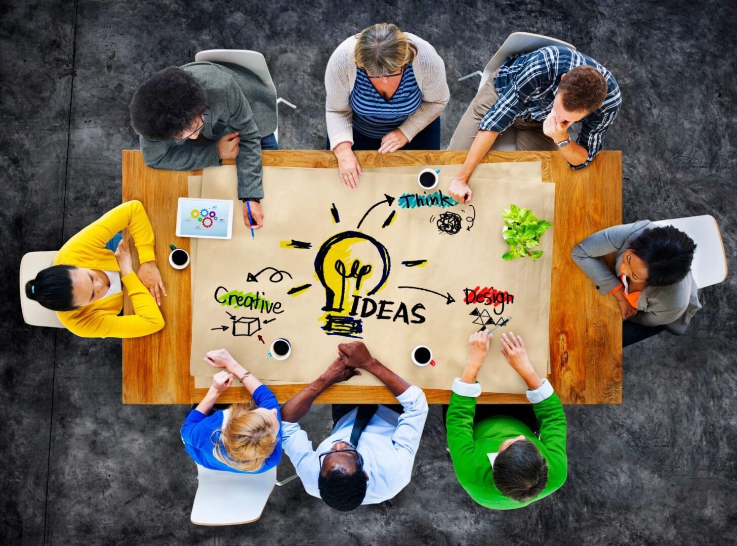 A group of people sitting around a table with an idea written on it.